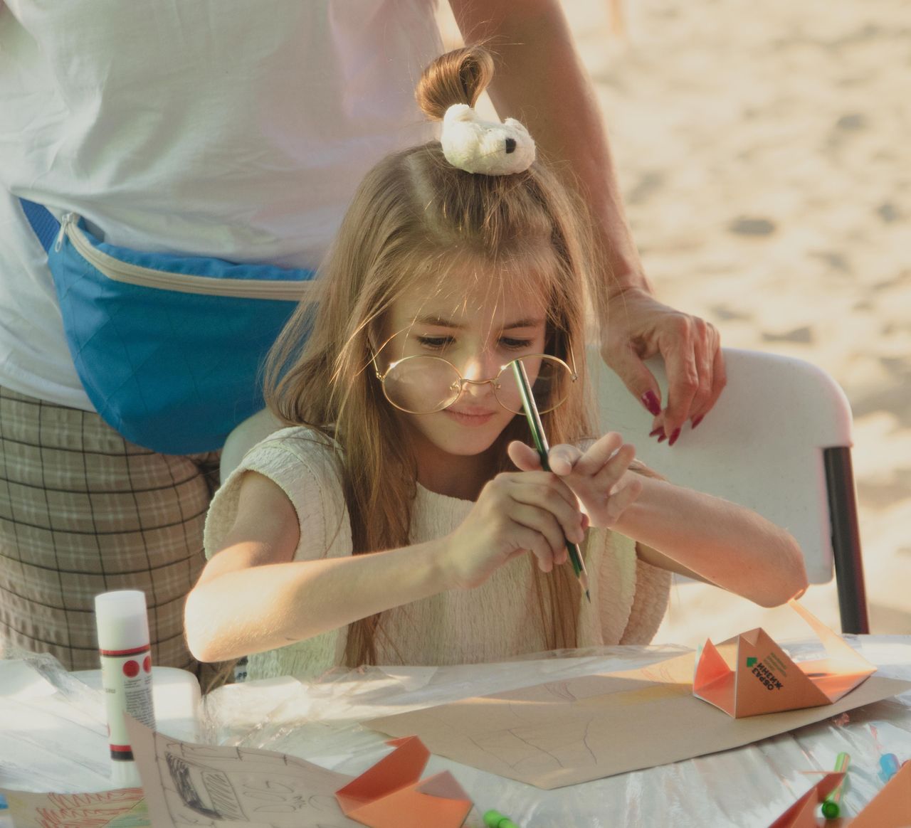 Child having fun with crafts at a summer outdoor event. Engaged in cutting and gluing paper.