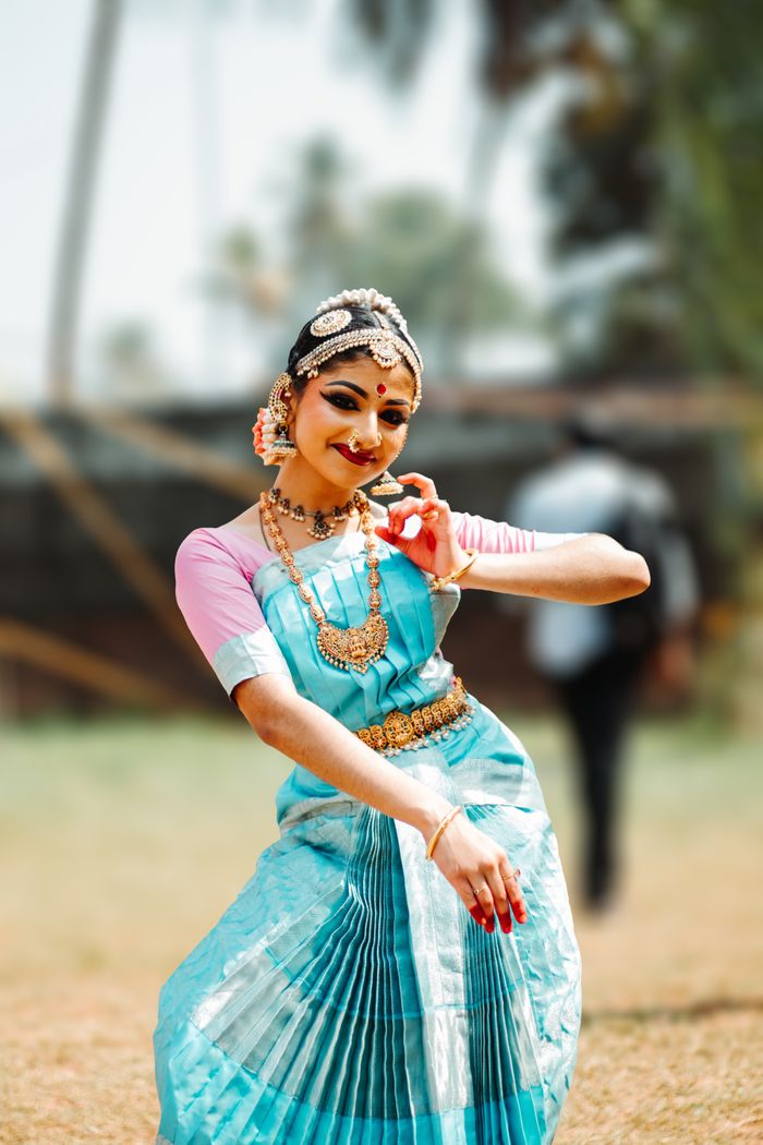 A woman in traditional Indian attire performing a dance outdoors, showcasing cultural heritage.