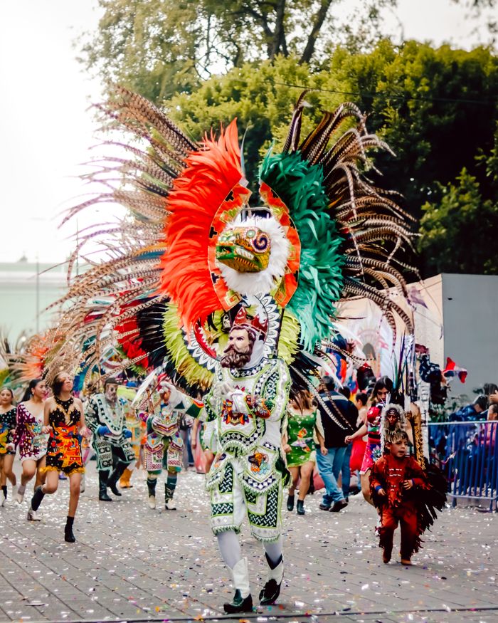 Colorful festival parade showcasing traditional feathered costumes and vibrant cultural dance.