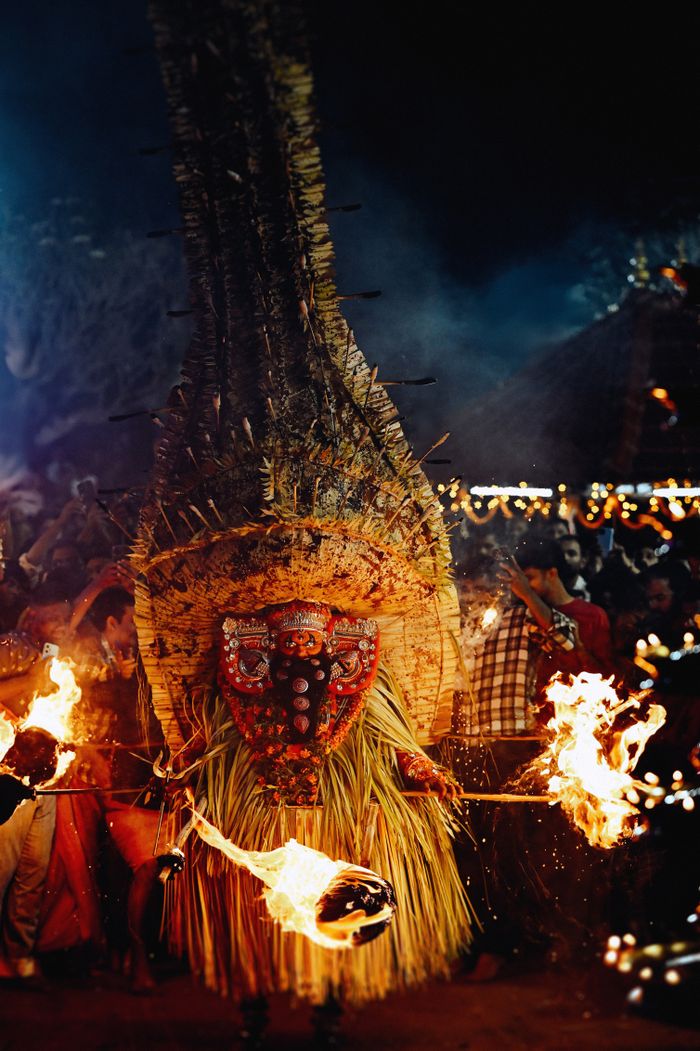 Vibrant cultural festival with traditional masked dancer performing a fire dance at night.