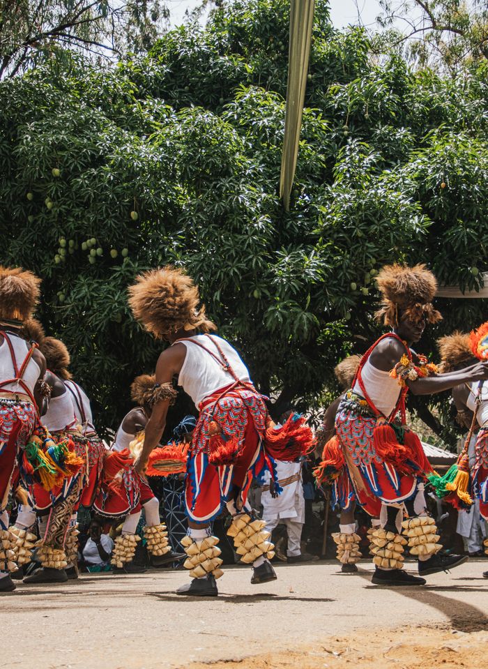 Colorful African traditional dance performance outdoors under greenery.