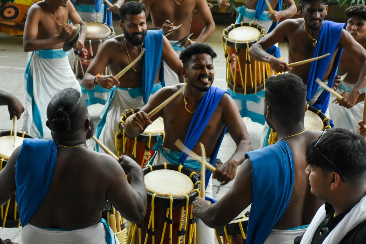 Men playing traditional drums at a cultural festival in vibrant attire, showcasing unity and ethnic heritage.