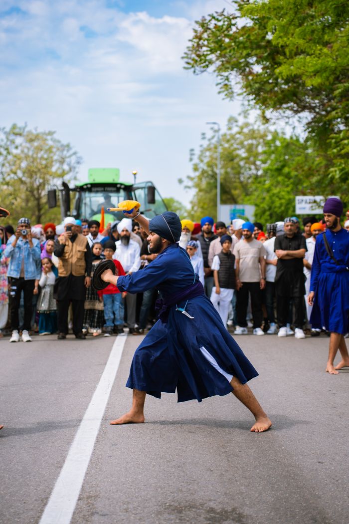 A group showcasing traditional martial arts in vibrant attire at a cultural festival, captivating an outdoor audience.
