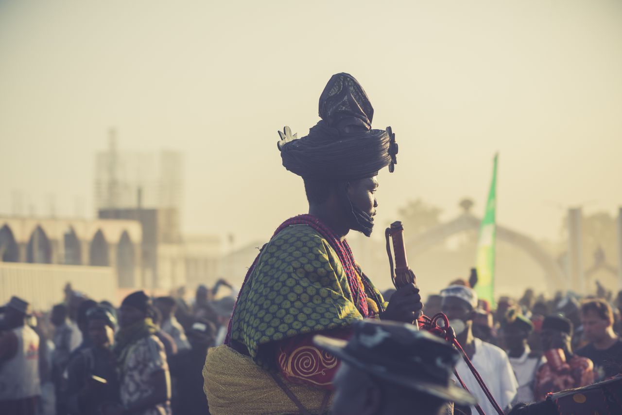 A vibrant festival with people in traditional attire at sunrise.