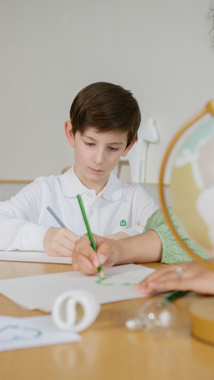 Young boy concentrates on writing task indoors at a desk during a study session.