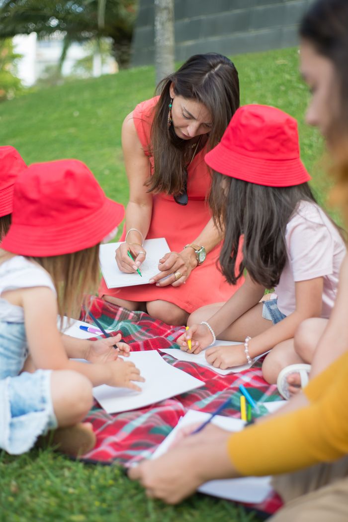 Group of children and adult drawing at a picnic outdoors. Lifestyle and creativity.